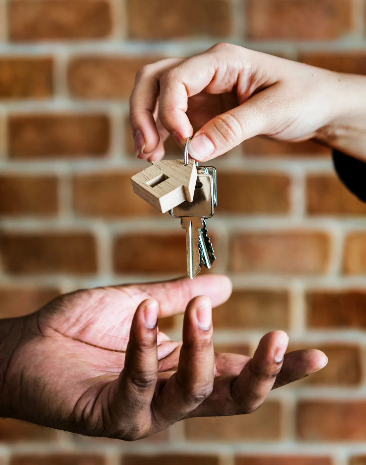 Schlüsselübergabe vor geöffneter Haustür eines Hauses